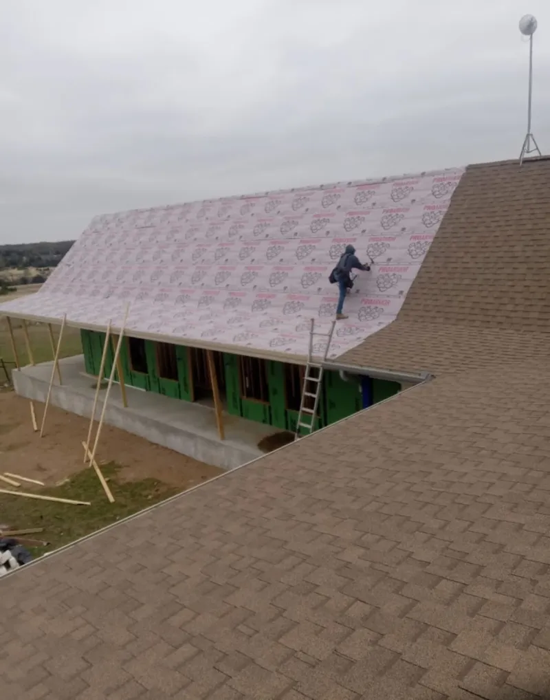Worker preparing underlayment for a metal roof installation in Alexandria